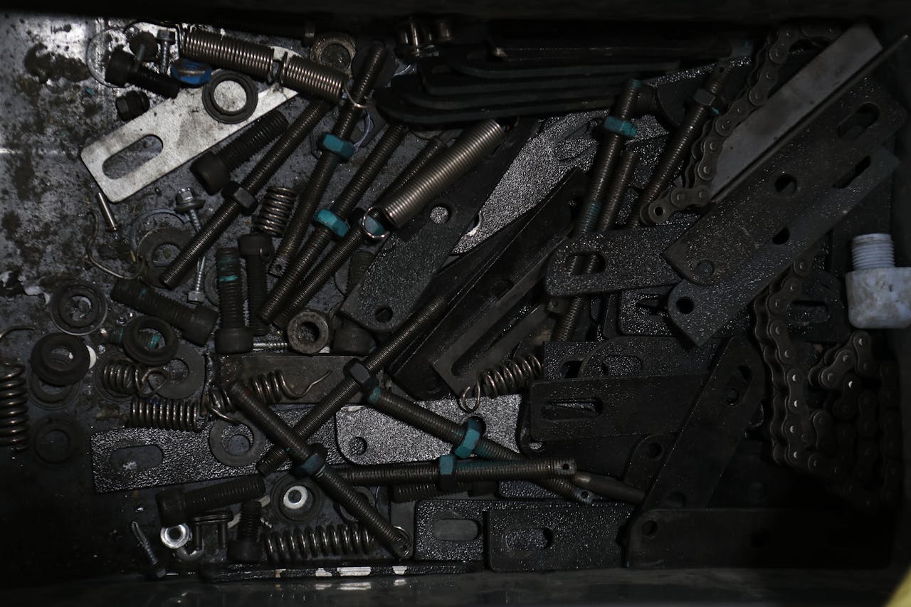 High-angle view of assorted metal fasteners, springs, and chains in a box.